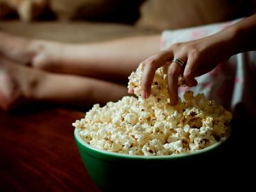 Nő belenyúl a pattogatott kukoricás vödörbe