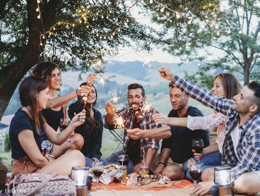 barátok a szabadban vacsoráznak és csillagszórót tartanak a kezükben