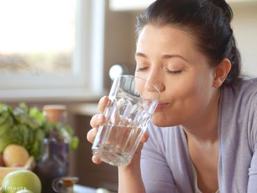 nő vizet iszik egy pohárból