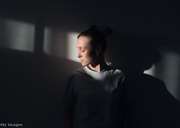 nő a homályban, arca előtt fénysugárral