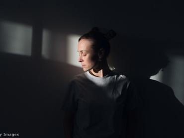 nő a homályban, arca előtt fénysugárral