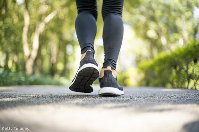 Nő a parkban, betonozott felületen gyalogol, de csak a lába látszik sportcipőben