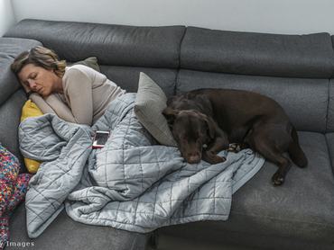 nő a kanapén alszik, kutyája a lábánál