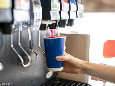 Papírpoharat tölt egy ember egy gépből üdítővel