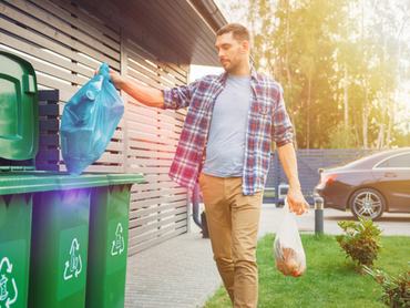 szemetet visz ki egy férfi a hulladékgyűjtő edényekbe