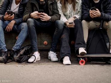 Fiatalok ülnek egymás mellett a mobiljukat nyomkodva