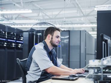 Informatikusként dolgozó férfi ül a számítógép mögött