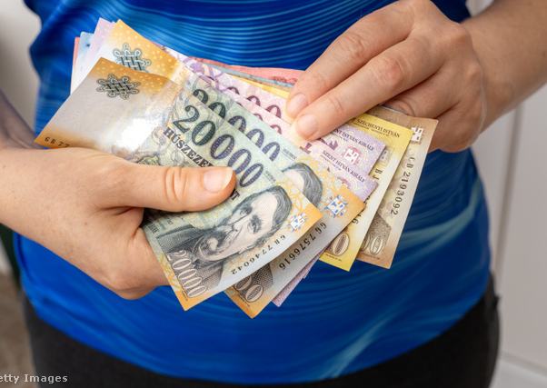 Női kéz magyar forintos bankjegyeket tart a kezében