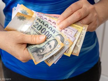 Női kéz magyar forintos bankjegyeket tart a kezében