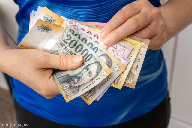 Női kéz magyar forintos bankjegyeket tart a kezében