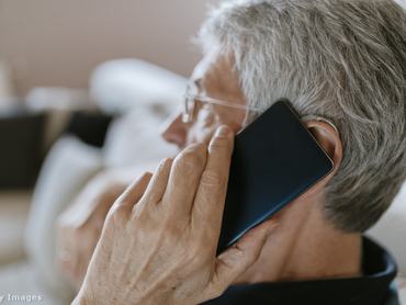 egy idős, ősz hajú férfi telefonál