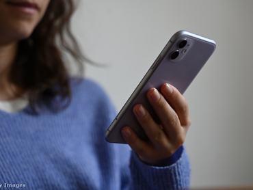 Egy nő mobiltelefont tart a kezében