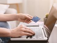 ember laptopon gépel, a kezében a bankkártyája