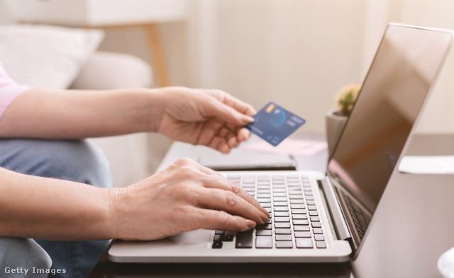 ember laptopon gépel, a kezében a bankkártyája