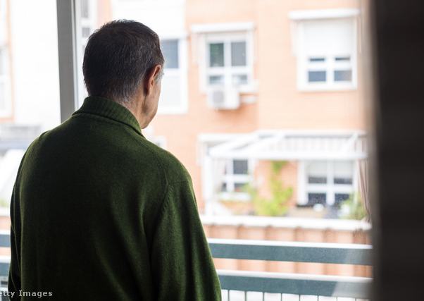 szomorú idős férfi áll az ablaknál