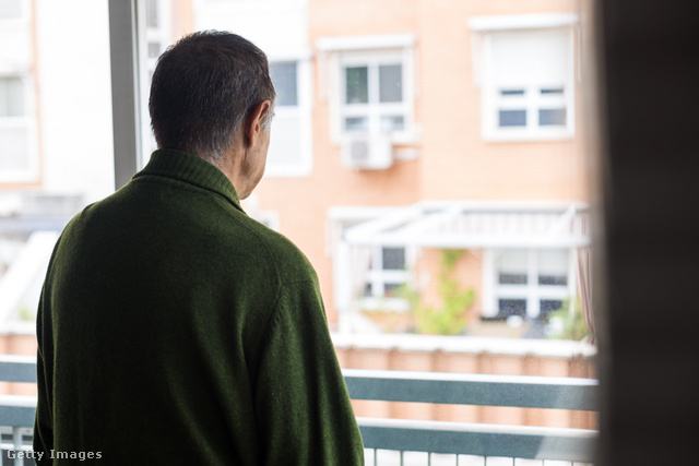 szomorú idős férfi áll az ablaknál