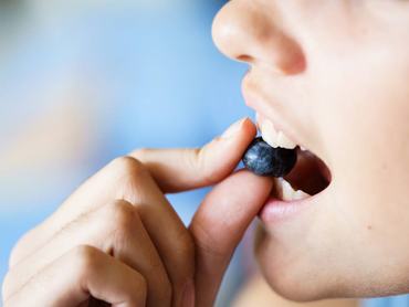 Közeli kép egy nőről áfonyaevés közben