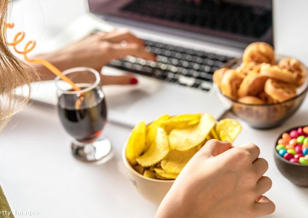 Nő laptopon dolgozik közben nassol.