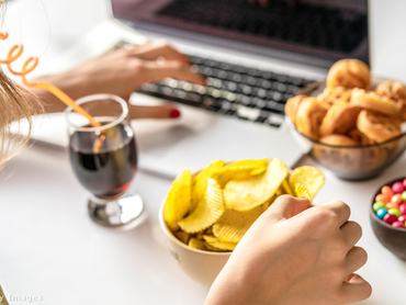 Nő laptopon dolgozik közben nassol.