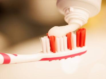 Közeli kép arról, hogy valaki fogkrémet nyom a fogkefére