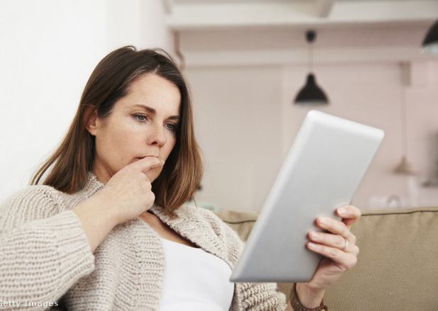 Egy nő elgondolkodva nézi a tabletjét