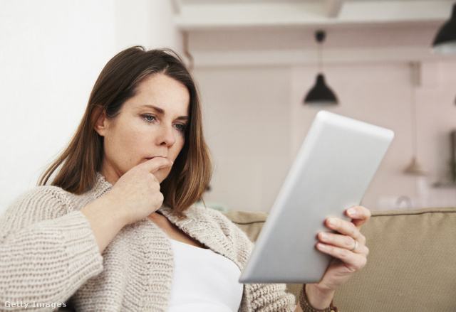 Egy nő elgondolkodva nézi a tabletjét