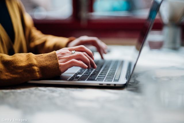egy nő gépel az asztalnál ülve, csak a keze és a laptop látszik