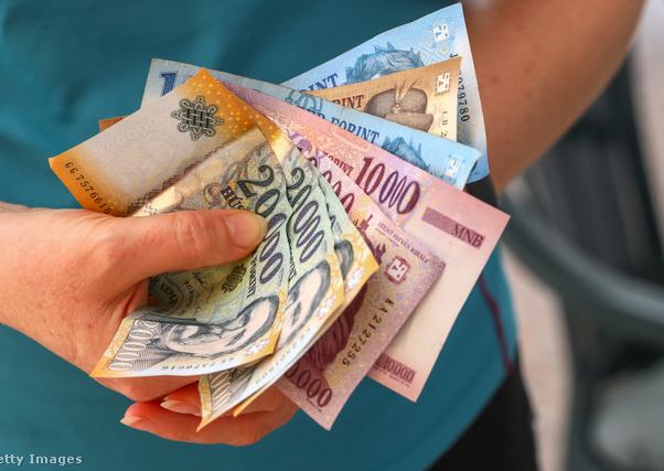 Egy nő forint papírpénzt tart a kezében
