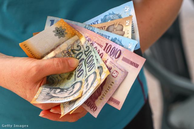 Egy nő forint papírpénzt tart a kezében