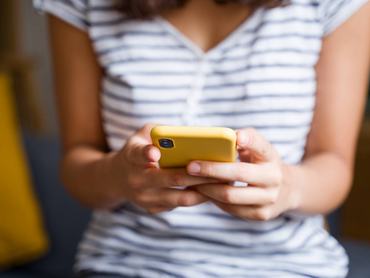 Egy nő mobiltelefont tart a kezében.