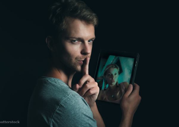 Egy férfi egyik kezében tablettel, a másikkal csendet mutat