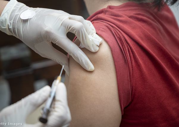 oltást ad be egy gumikesztyűs orvos a betegnek, akinek csak a válla látszik