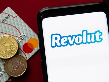 Revolut a mobiltelefon kijelzőjén, bankkártya és aprópénz