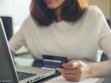 egy nő netes átutalást hajt végre a laptopján, az asztalnál ülve