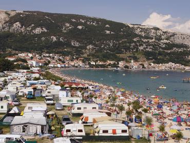 egy nyaralóhely látképe tengerparttal és lakókocsikkal a nyári napsütésben, a strandon sok napernyő