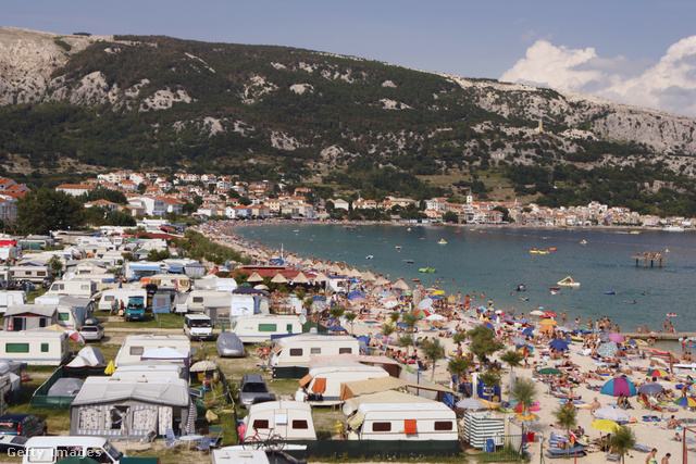 egy nyaralóhely látképe tengerparttal és lakókocsikkal a nyári napsütésben, a strandon sok napernyő