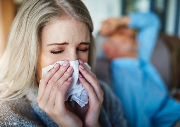 Fiatal nő zsebkendőbe tüsszent