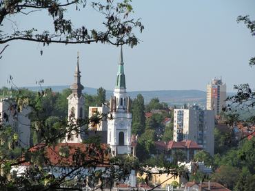Kilátás Miskolcra toronyházakkal, templomtornyokkal és fákkal.