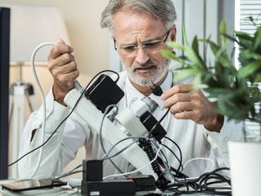 Businessman looking for free socket in overcrowded power board