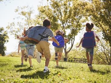 gyerekek rohannak a szabadban, iskolatáskával