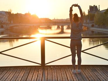 Nő edz a Pont des Arts hídon Párizsban naplementekor.