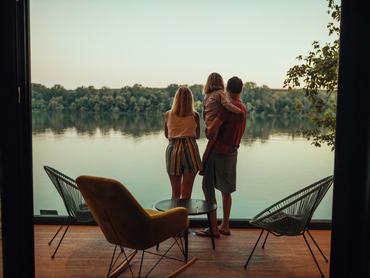 A scenic view of family from inside of weekend cottage by the riverside