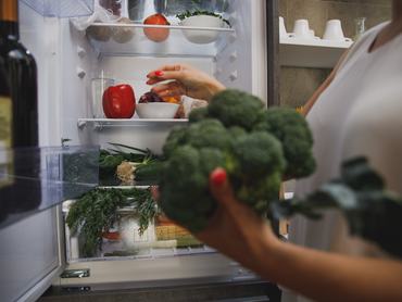 egy nő áll a nyitott hűtő előtt