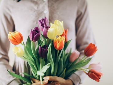 Egy nő egy csokor színes tulipánt tart a kezében