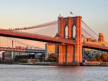 This view from South Street Seaport in Lower Manhattan looks across the East River at sunset toward Brooklyn and Manhattan Bridges.