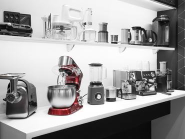 Household appliances for the kitchen. Sale of electrical equipment for cooking at home. Coffee makers, mixers, meat grinders, blenders, coffee machines, toasters and kettles on a shelf in the interior.