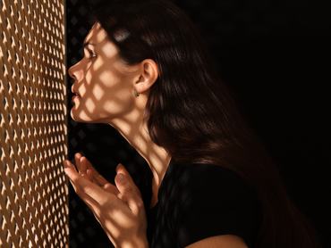 Woman talking to priest during confession near wooden partition in booth