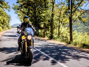Biker with full safety gear enjoys ride on country road