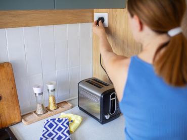 Woman using toaster to make breakfast in kitchen at home