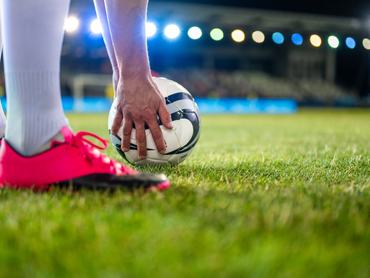 Pályán focilabdát tesz le a játékos